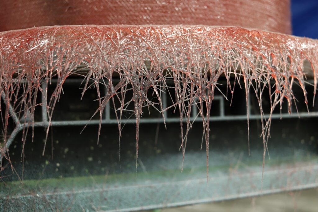 Fiberglass overspray hangs off a boat mold